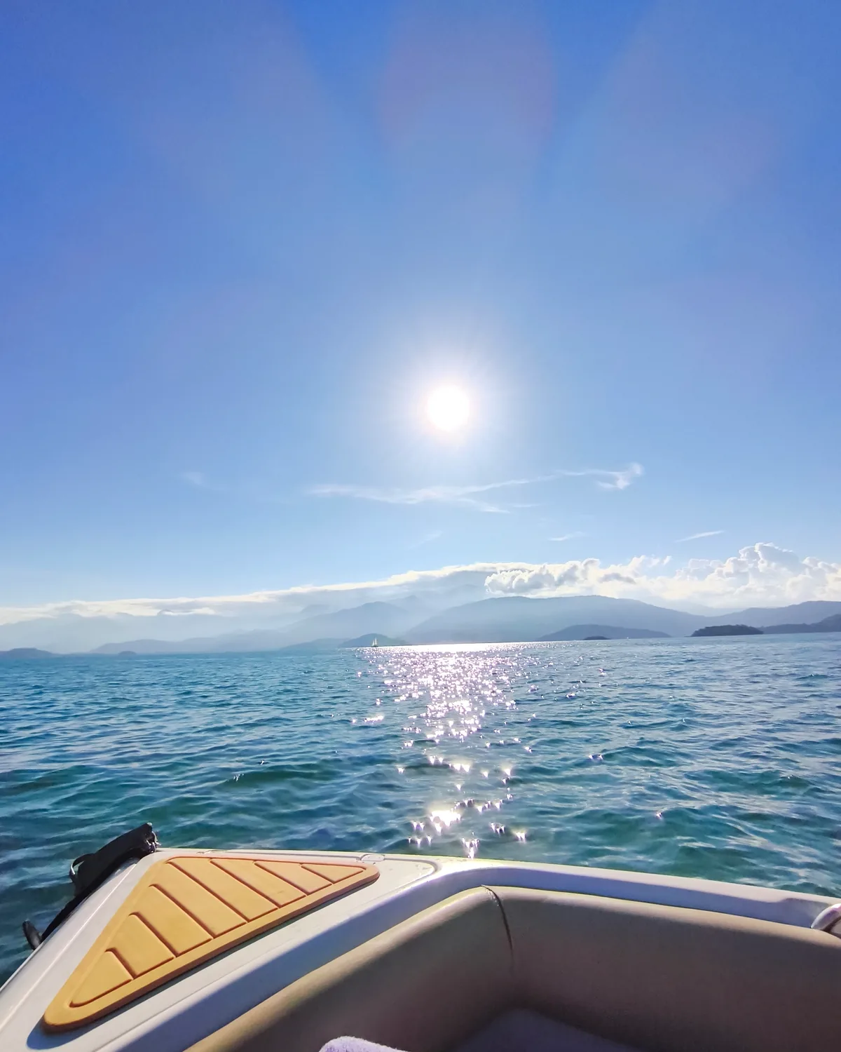 Sol refletido no mar visto de bordo da Lancha Oceania, com as ilhas ao fundo